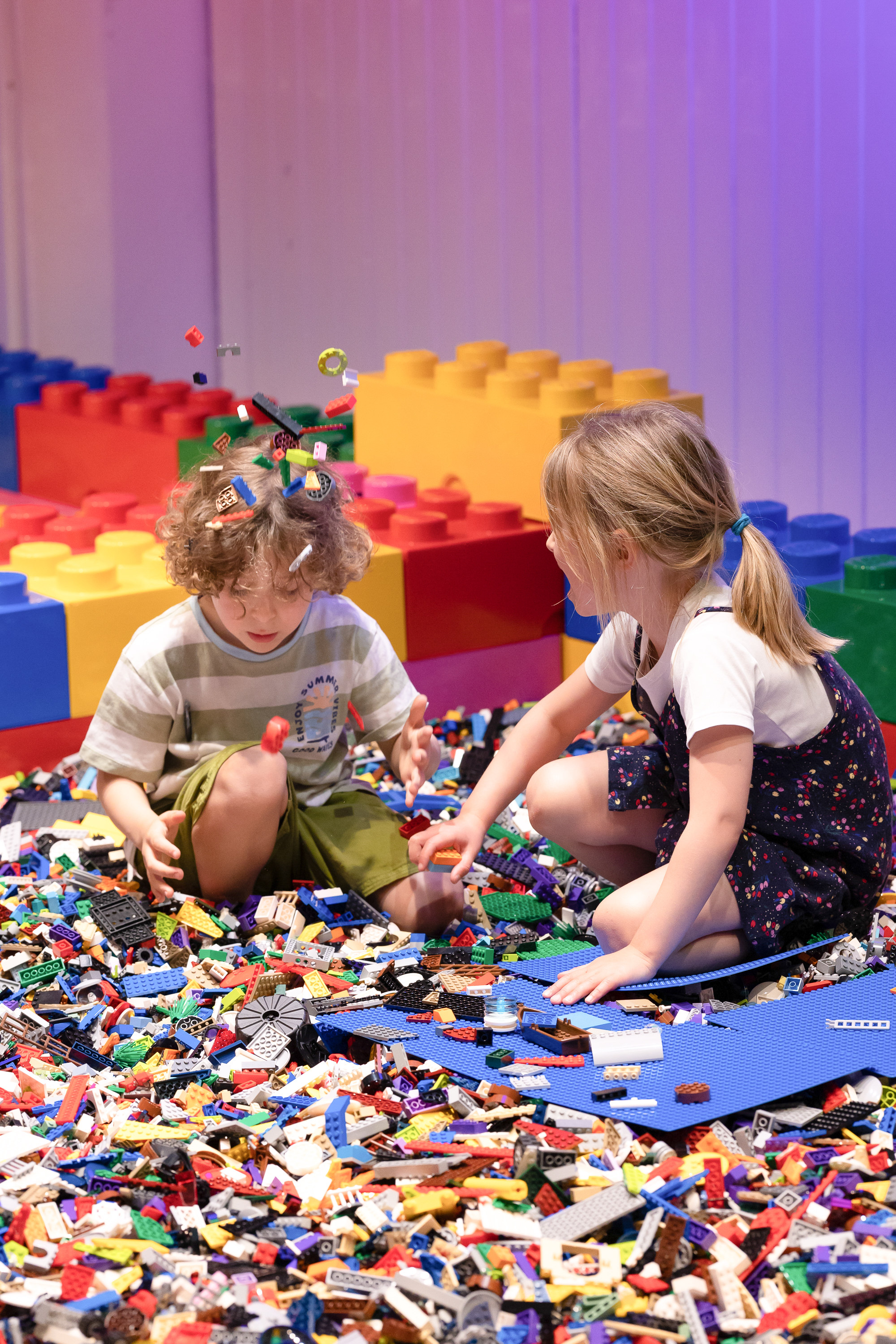 Deux enfants construisent au milieu de briques colorées dans la PlayZone de l'exposition.