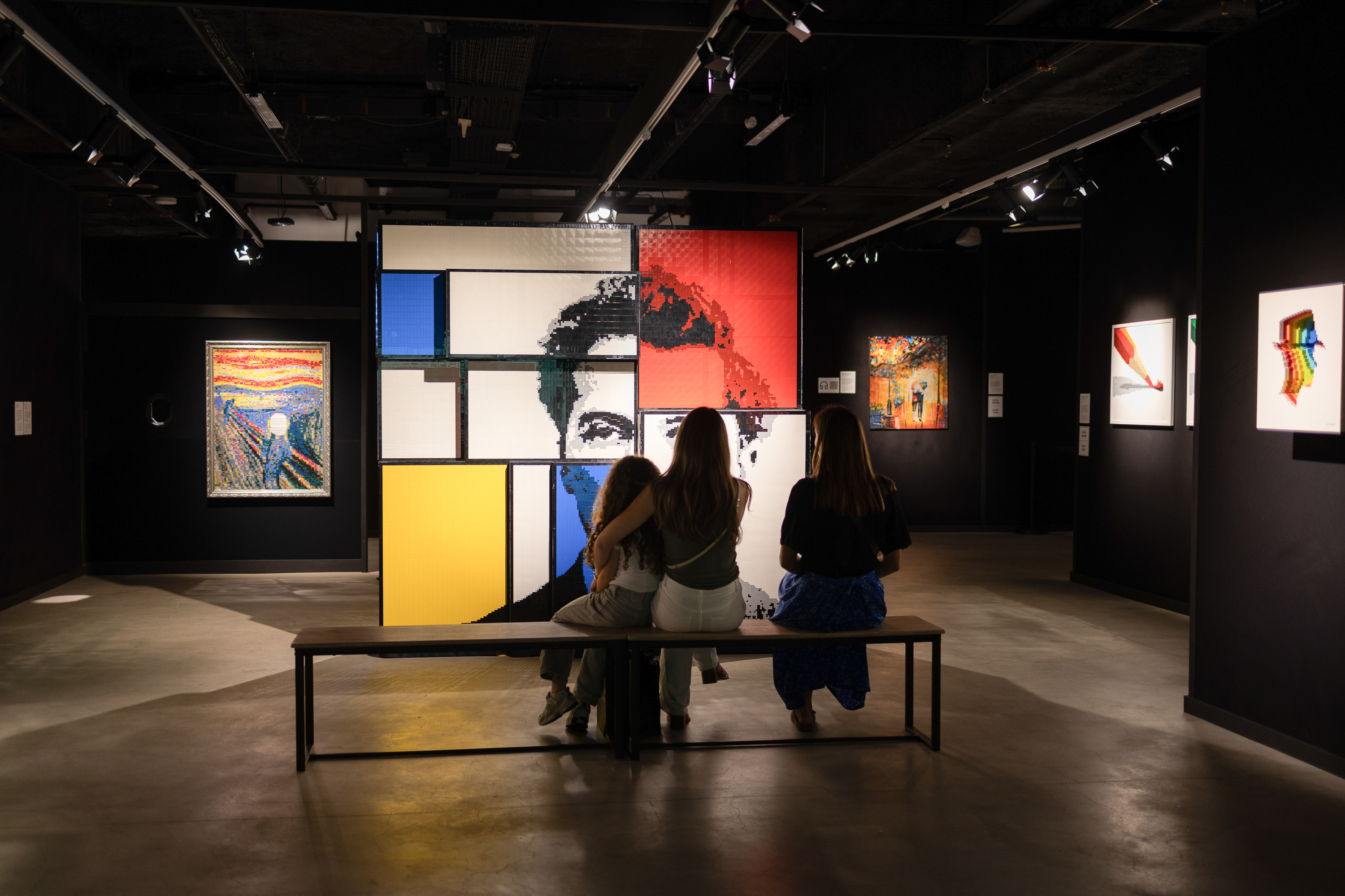 Des visiteurs regardent une installation monumentale en briques inspirée de Mondrian, entourée d'autres œuvres.