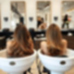 friends doing their hair side by side at the shampoo bowls at a salon.jpg