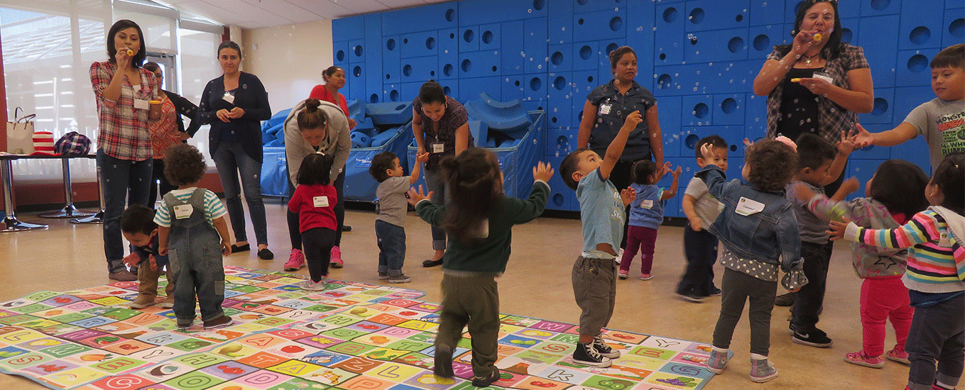 Habla Conmigo kids, educators, and parents, playing and blowing bubbles.
