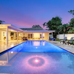 Modern house with pool at dusk, Landscaping & Lighting, outdoor chairs, and trees.