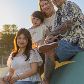 A warm family portrait with golden sunset light highlighting their hair as they snuggle close together