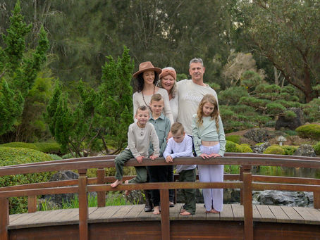 Multi-generational family photo at Edogawa Japanese Gardens, Central Coast — grandparents, mum, and four children standing together on the wooden bridge during a relaxed family photography session.