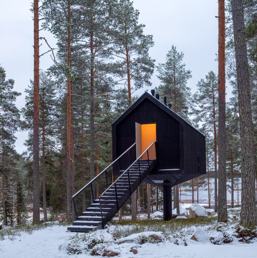 "Niliaitta is a prototype cabin designed by Studio Puisto Architects for the Kivijärvi Resort near Finland's Salamajärvi National Park. Completed in 2020, the cabin is part of a larger, ecologically sensitive tourism project that will eventually feature up to 50 unique dwelling units, as well as a sauna and conference center.

The design is a modern interpretation of the traditional niliaitta, an elevated wooden hut historically used by the indigenous Sámi people to store food and other items away from bears and other wild animals. Niliaitta was conceived as a secluded, ""bear-cache"" for humans, providing a retreat from the chaos of modern life. The cabin is elevated on a single, slender concrete-filled steel column, which minimizes its footprint and allows the forest floor to remain undisturbed.  The exterior is clad in black-toned pine, allowing the structure to blend with the surrounding trees, while the interior is lined with warm, light-toned wood.

The 30-square-meter cabin features a minimalist and cozy interior, with all utility spaces—including a kitchenette, spacious shower, and building systems—cleverly contained within a central core. The central core design allows the living space to remain open and uncluttered, drawing attention to a full-height window that frames views of the surrounding nature. The interior also features wood surfaces and eco-wool insulation, with plastic avoided in the structure. A linear staircase provides access to the elevated cabin, creating a transition from the wild outdoors to a secure and tranquil retreat. 

Credits
Architects: Studio Puisto Architects
Structural Engineer: BD-Con Oy
HVAC Designer:  LVI-insinööritoimisto Jorma Niemonen Oy 
Photography: Marc Goodwin-Archmospheres
Electrical Designer: Karawatski Oy"