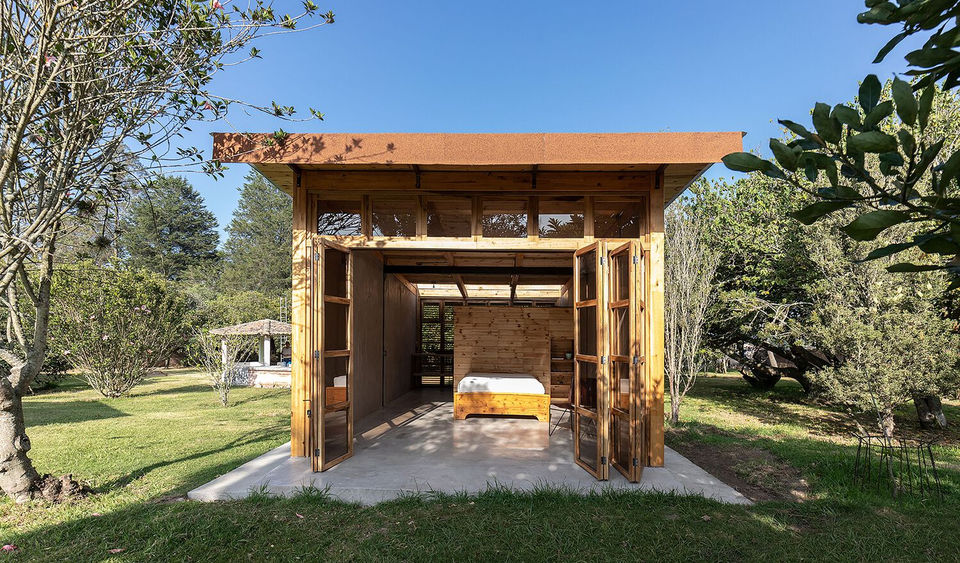 "The Guayabamba Cabin is a micro-architecture project located in the rural parish of Guayllabamba, Ecuador, an hour outside the city of Quito. Completed in 2021 by Quito-based architectural firm Rama Estudio, the cabin is a small, 33-square-meter wooden structure designed to blend into its surroundings while prioritizing sustainability and a connection with nature.
Constructed with wood and a traditional Latin American technique called bahareque, which uses earth, straw, and wood, the cabin was designed with the intention of reclaiming local construction practices. This approach not only strengthens its connection to the land but also optimizes resources through material experimentation. The building is clad in small wooden panels, which give the structure a simple and timeless aesthetic. A central outdoor space and an elevated platform for the cabin allow it to connect seamlessly with the landscape and offer peaceful views of the lush green fields.
The cabin was designed as a ""hospitality"" project, with a focus on creating a sustainable and adaptable retreat. This focus is part of Rama Estudio's broader architectural philosophy, which centers on sensitive approaches to natural context and resource optimization. The firm, co-founded by Felipe Donoso, Carolina Rodas, and Carlos Chávez, often integrates sustainable building materials like rammed earth, bamboo, and wood into its projects, reflecting a deep respect for the land and traditional building methods.
Credits:
Architects: Rama Estudio (Felipe Donoso, Carolina Rodas, Carlos Chávez)
Photography: JAG Studio
"