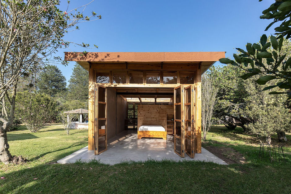 "The Guayabamba Cabin is a micro-architecture project located in the rural parish of Guayllabamba, Ecuador, an hour outside the city of Quito. Completed in 2021 by Quito-based architectural firm Rama Estudio, the cabin is a small, 33-square-meter wooden structure designed to blend into its surroundings while prioritizing sustainability and a connection with nature.
Constructed with wood and a traditional Latin American technique called bahareque, which uses earth, straw, and wood, the cabin was designed with the intention of reclaiming local construction practices. This approach not only strengthens its connection to the land but also optimizes resources through material experimentation. The building is clad in small wooden panels, which give the structure a simple and timeless aesthetic. A central outdoor space and an elevated platform for the cabin allow it to connect seamlessly with the landscape and offer peaceful views of the lush green fields.
The cabin was designed as a ""hospitality"" project, with a focus on creating a sustainable and adaptable retreat. This focus is part of Rama Estudio's broader architectural philosophy, which centers on sensitive approaches to natural context and resource optimization. The firm, co-founded by Felipe Donoso, Carolina Rodas, and Carlos Chávez, often integrates sustainable building materials like rammed earth, bamboo, and wood into its projects, reflecting a deep respect for the land and traditional building methods.
Credits:
Architects: Rama Estudio (Felipe Donoso, Carolina Rodas, Carlos Chávez)
Photography: JAG Studio
"
