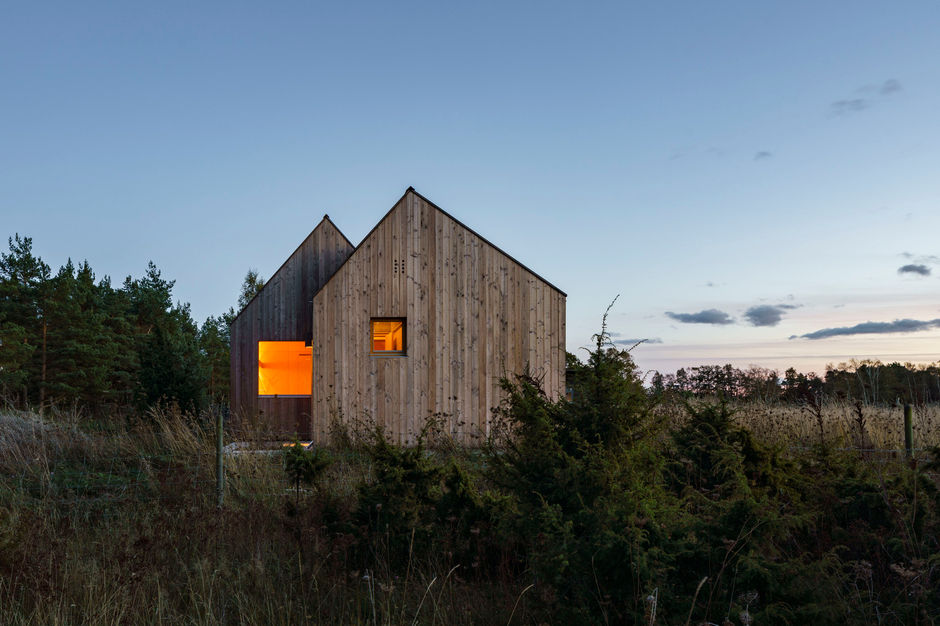The Field House, a project by Lookofsky Architecture completed in 2020 on the Swedish island of Fårö, is a contemporary take on the area's traditional fishermen's huts and farmhouses. Instead of a single, large structure, the design is composed of several small, interconnected timber volumes, each with a distinct purpose, such as a bedroom unit, a communal living area, or a reading room. This clustered arrangement is a modern interpretation of local settlement patterns and allows for flexible expansion with additional units in the future.
The house stands on a continuous concrete platform that also serves as the interior flooring, echoing Gotland's characteristic limestone bedrock. The exterior is clad in solid larch wood boards, a regional tradition, which will naturally weather from a golden brown to a silver-grey color over time. Inside, the walls are covered in birch plywood, which provides a warm and inviting contrast to the bare concrete floor. The interiors are characterized by an austere minimalism, with storage and furniture seamlessly integrated into the walls to emphasize the simple intersecting surfaces. Large, frameless windows and a sliding door create carefully framed views of the surrounding field, fostering a sense of continuity between the house and the natural landscape.
Credits
Architects: Lookofsky Architecture
Builder: Indecon Home
Photographs: Mattias Hamrén