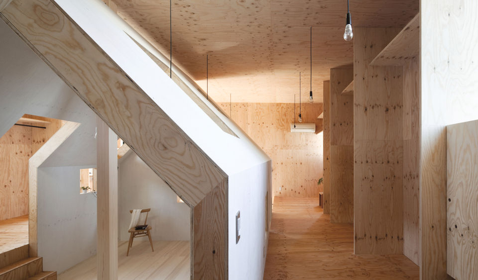 "The Ant-house, a single-family residence in Omaezaki-City, Shizuoka Prefecture, Japan, was completed in 2012 by mA-style architects. Designed for a family of five, the 66-square-meter home presents a stark, dark metal-clad cube to the street, with a single, unassuming entryway. However, the interior is a warm, labyrinthine world of larch plywood, filled with natural light from carefully placed skylights and apertures.
The design is based on the concept of a house-within-a-house, with a two-story, gabled-roof structure nestled inside the exterior cube. This creates a playful and ambiguous interior, devoid of typical wall partitions, which allows for free-flowing use of the space and encourages interaction among family members.
The interior layout features a lower-level living room, kitchen, dining area, bathroom, and storage spaces, with bedrooms located on the upper level, separated by a free, double-height space that connects the floors. This central gabled space, with openings in its walls, allows natural light and air to permeate the home, creating a dynamic and cozy atmosphere. The unique spatial arrangement challenges traditional notions of a room, allowing the family to define and use the space as they wish.
Credits
Architects: Atsushi Kawamoto and Mayumi Kawamoto, mA-style architects
Photography: Kai Nakamura"