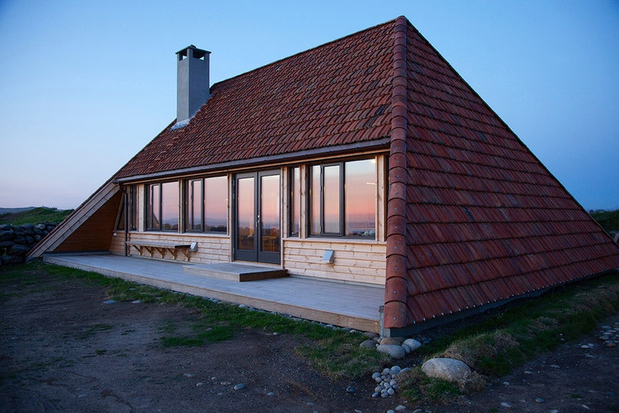 The Selestranda House is a residential renovation and extension project located in Time, Norway, near the scenic southwest coast. Completed in 2016 by bark arkitekter, the project breathed new life into a 50-year-old cottage, originally designed in 1961 by architect Atle Sørby. The renovation successfully balanced the building's historical integrity with the functional demands of modern living. 

The house sits on a relatively flat plot surrounded by the distinctive landscape of the region, featuring long sloping fields, beaches, and dunes separated by old drystone walls. Its proximity to the shoreline places it within a landscape-preservation area, which meant the architects worked closely with local authorities during the building process. 

The architectural approach involved respecting the original design while modernizing the interior and expanding the living space. The cottage's original pitched roof with pulled-down gables, a reinterpretation of the traditional "Jærhus" typology, was preserved. This design is crucial for withstanding the harsh local weather conditions. 
To maintain this connection to the past, local craftsmen carefully removed, stored, and re-laid the original roof tiles, which were sourced from local brick factories. 

The renovation involved a strategic reorganization of the interior space. The walls and ceiling of the main volume were opened up to create a single large, open-plan common area. This space now accommodates the living, dining, and kitchen functions, creating a bright and expansive atmosphere.
A new 88 m² annex was constructed to house private functions. This addition includes a bedroom, a bathroom, and a storage room, allowing for a clearer separation of public and private zones within the home.
Large glass windows were installed to maximize natural light and offer the homeowners uninterrupted views of the surrounding coastal scenery. 

The interior features a minimalist, no-frills aesthetic, with a neutral color palette and light timber finishes creating a calm and functional living space. The architects focused on simple, high-quality materials to complement the building's modest scale. 

Project credits
Architects: bark arkitekter
Architect in Charge: Katrine Grimnes
Original Architect: Atle Sørby (1961)
Location: Time, Norway
Project Year: 2016
Photographs: Lise Bjelland
Manufacturers: Minera, E.W. Andersen, Hamran Kjøkken, Riska Sagbruk, Vikeså Trevare