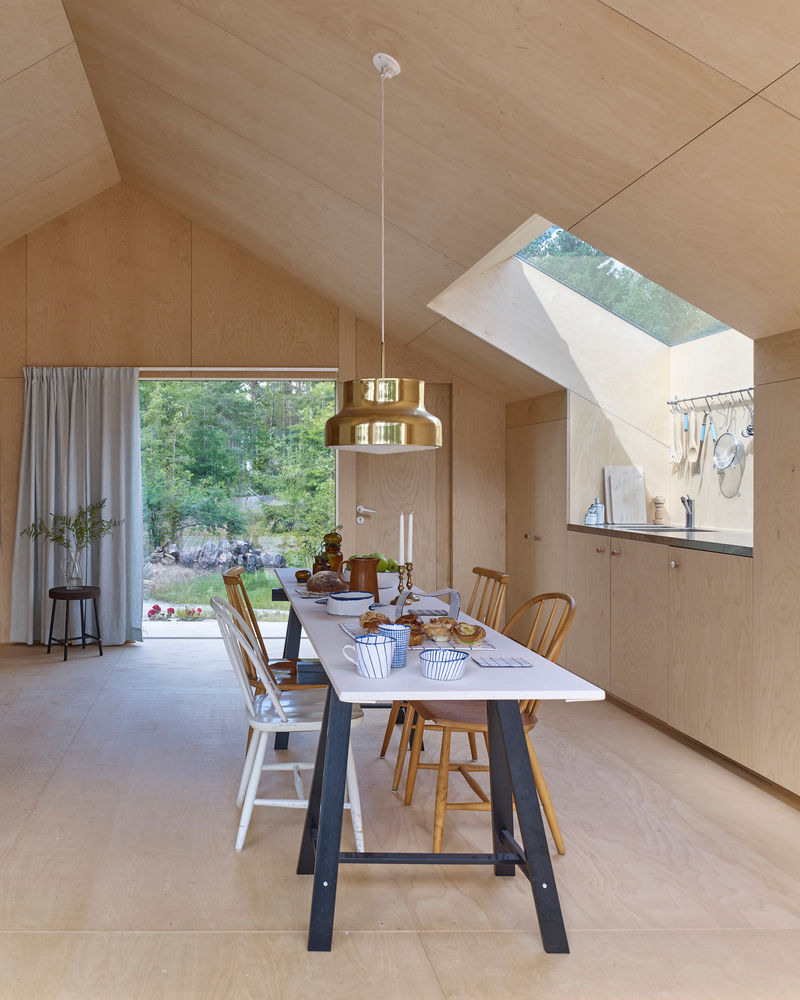 The Kaggeboda House, a summer retreat designed by Stockholm-based AndrénFogelström in collaboration with Kolman Boye Architects, is a unique arrangement of three separate cabins nestled in the Stockholm archipelago. Completed in 2013, the design is centered on encouraging an intimate connection with nature by requiring residents to step outside to move between different living areas. The house offers a modern take on the traditional Swedish summer cottage, with a decentralized layout that has gained particular relevance for its innovative approach to small-scale living.



The project is conceptualized as a "mini village" where three cabins of varying sizes are arranged in close relation to one another on a shared wooden deck. The dark, strong exterior and light, simple interior are designed to harmonize with the surrounding pine forest and the rocky terrain of Norrtälje, Sweden.


Exterior: The facades are clad in a dark, phenol-coated plywood, typically used for forming concrete, which gives the cabins a distinctive, weather-resistant finish. The doors, also dark and industrial, are made from the same metal sheeting used for the roofs.
Interior: In contrast to the tough exterior, the interiors are bright, warm, and serene, clad entirely in white-waxed birch plywood. The attention to detail is evident in the seamless, custom-built furniture and aligned wood joints, which give the space the feel of a meticulously crafted object.
The three buildings serve distinct purposes:
Main Cabin: The largest of the three contains an open-plan living room, kitchen, bedroom, and dining area, all centered around a wood-burning stove.
Mid-size Cabin: The second building houses a study and a guest room.
Smallest Cabin: The third cabin is used for storage but was designed to be flexible enough to be converted into a bathroom if needed.


Outdoor living: The wooden deck connects the cabins and functions as an extension of the living space, featuring various lounge areas and an outdoor kitchen. The arrangement emphasizes outdoor living and the simple beauty of a summer spent close to nature.


Project credits and contributors
Project Name: Kaggeboda
Project Location: Norrtälje, Sweden
Completion Year: 2013
Architects: AndrénFogelström and Kolman Boye Architects
Lead Architects: Tove Fogelström and Erik Kolman
Area: 62 square meters
Manufacturers: AutoDesk and karnsund
Photography: James Silverman