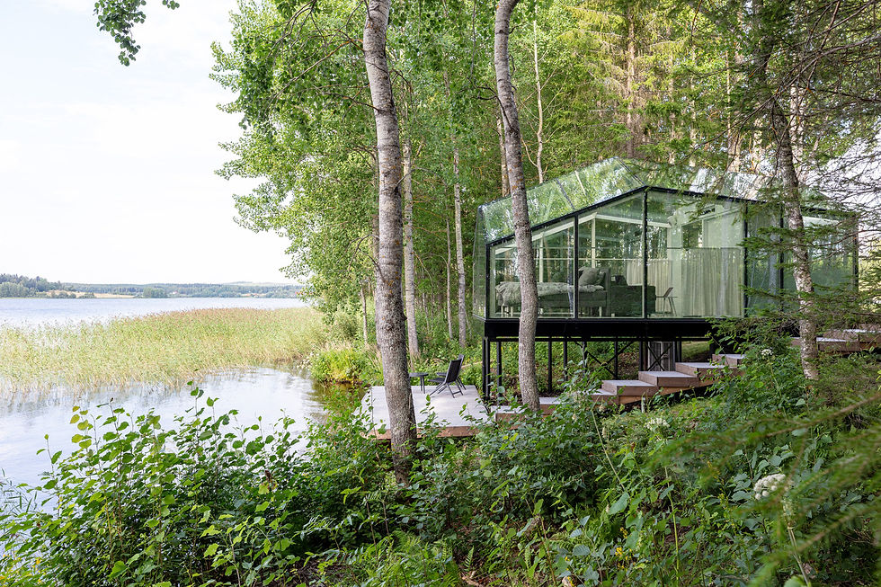 "The Lucia Smart Cabin is a 24-square-meter glass-and-steel modular unit designed in 2019 by Finnish firm Pirinen Salo Oy for the glass construction company Savon Lasituote Oy. Conceived as a high-quality ""hideout"" or experiential space, the cabin was created to offer occupants uninterrupted, panoramic views of the surrounding landscape, including the sky. The initial prototype was installed in Inari, Finland, near Juutuanvuono Lake, with an almost 360-degree vista of the riverside site.
A core principle of the design is seamless integration with nature. This is achieved through its mirrored glass exterior, which reflects the environment and makes the cabin appear to blend in with the trees. The sleek black steel frame and floor ribbon also minimize the visual impact on the landscape. The interior is designed to draw attention outwards, with uniform colors and materials that do not distract from the external view. The triangular shape of the steel beam structure and the angle of the glass surfaces are precisely calculated to optimize sightlines, especially for someone lying in bed.
High performance in challenging climates is a key feature of the Lucia Smart Cabin. The structure uses high-tech thermal glass, tested to withstand frigid temperatures, and includes an integrated heated floor system. Integrated lighting within the steel frame illuminates the interior without cluttering the glass and uses the surfaces to create a dynamic, multi-dimensional effect. For privacy or cooling, options such as curtains or customized prints can be added to the glass. The units are prefabricated and delivered to the site ready for installation on foundations with infrastructure connections. The compact but efficient interior accommodates a king-size bed, a small kitchenette, a dining area, and a bathroom. An exterior patio and a path to the water's edge extend the experience to the outdoors.
Credits
Architects: Pirinen Salo Oy (Teemu Pirinen, Lauri Salo)
Manufacturer: Savon Lasituote Oy (Kai Nikula, Jani Leinonen, Kari-Matti Ruhanen)
Construction Engineer: Hannu Nivalainen of Ylä-Savon Rakennesuunnittelu Ky
Constructor: Meserak Oy (Pekka Repo, Hannu Komulainen, Toni Komulainen)
Landscape Architects: VSU Maisema-arkkitehdit Oy (Outi Palosaari, Saara Oilinki, Katri Nuutinen)
Photography: Marc Goodwin
HVAC: Sami Säisä of Hanakat Iisalmen Putkiasennus Oy
Electrical Engineering and Implementation: Mikko Murtola of Iisalmen Sähkö- ja automaatiosuunnittelu Oy
Carpentry and Fixtures: Juha Huttunen with Miikka Bär from Vahtituvan puusepänverstas and B Design Oy
Fireplace and Chimney: Sydänmuuraus Oy
Interior Design (Red Cabin): Lomallo
Consultants: RP-Teollisuuspalvelu
Modular Building Solutions and Materials: Sika Finland (various Sika products)"