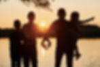 Family of four forming a heart at sunset, symbolising the family protection life insurance can offer with Arcadia’s guidance