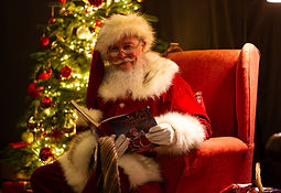 Smiling Santa in his grotto reading a story.jpg