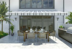 Grey and white striped awning shading an outdoor dining table with chairs on hot summer day