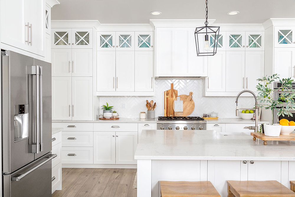 Luxury kitchen with white cabinets, stainless steel appliances, iron pendant light, marble covered island with wooden stools.
