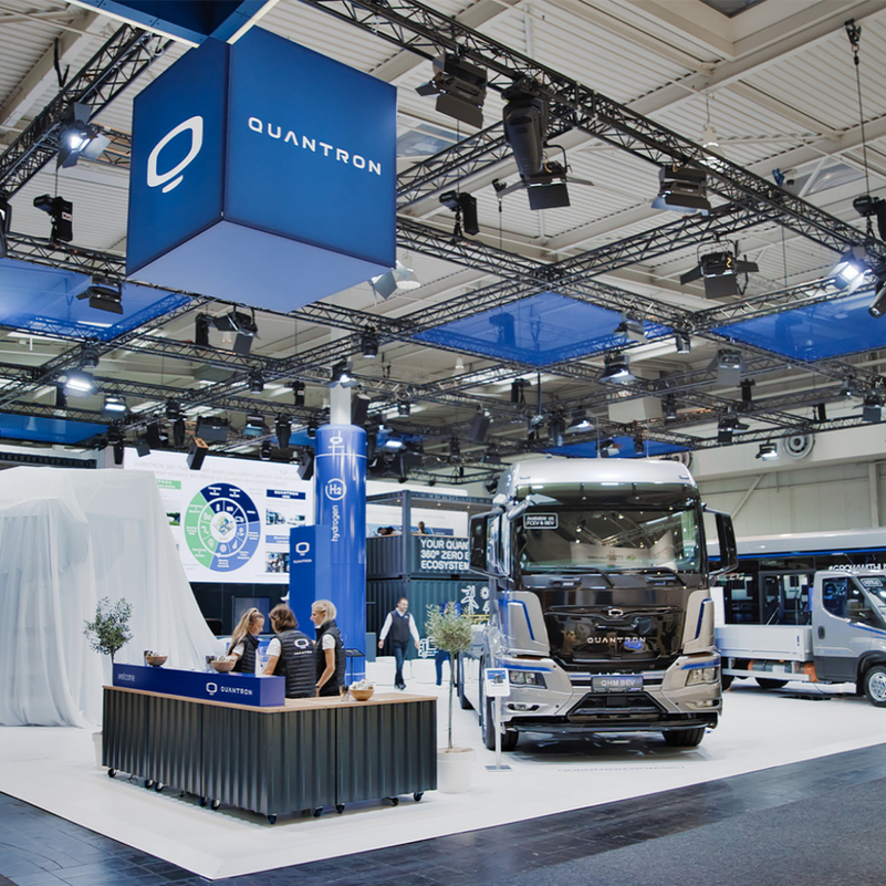 Messestand mit Übersehcontainer im Hintergrund und LKW im Vordergrund. 3 Frauen an einem Counter.