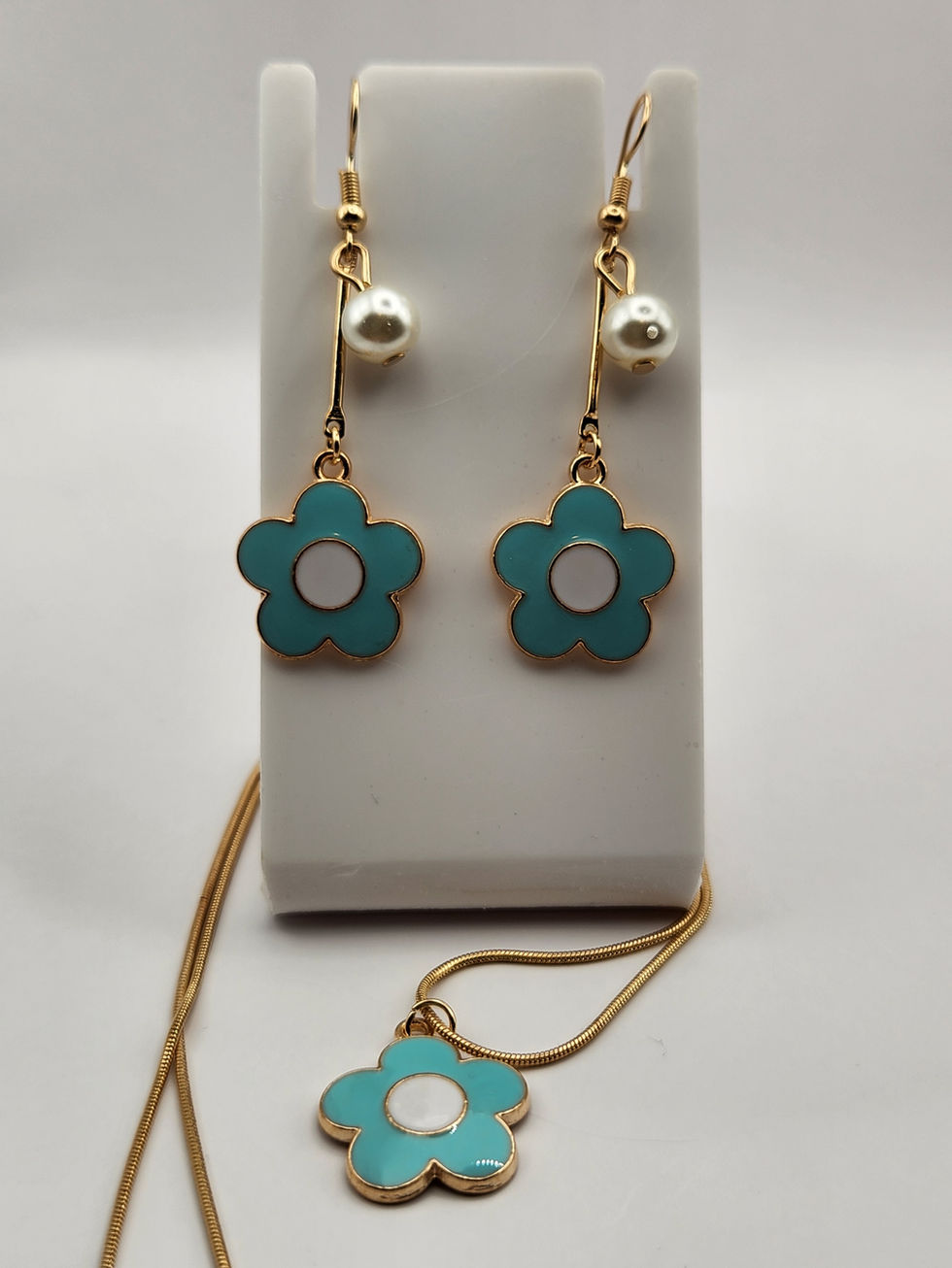 Teal flower earrings and necklace set with gold accents and white pearls.
