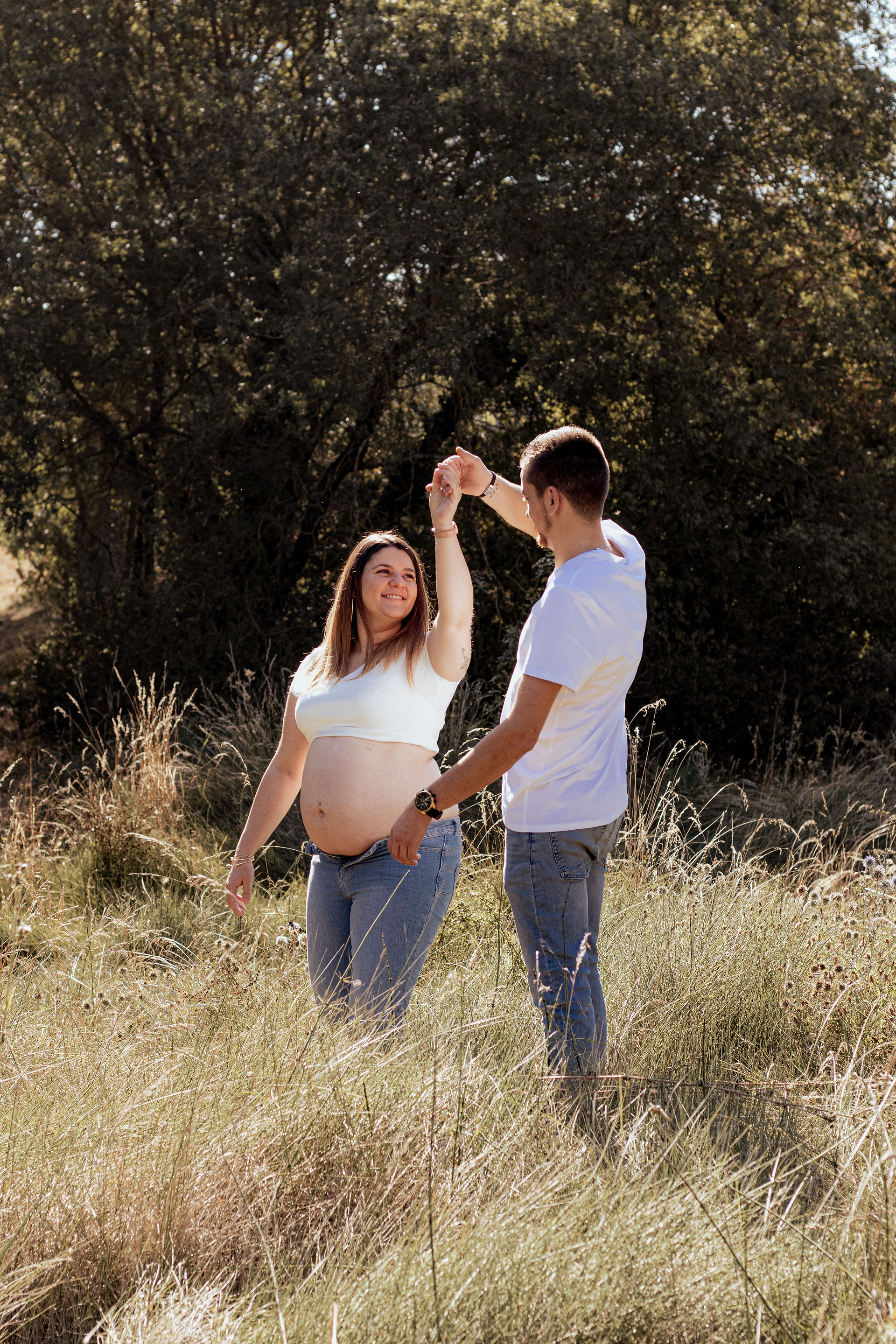 le futur papa fait danser sa femme enceinte dans un champ