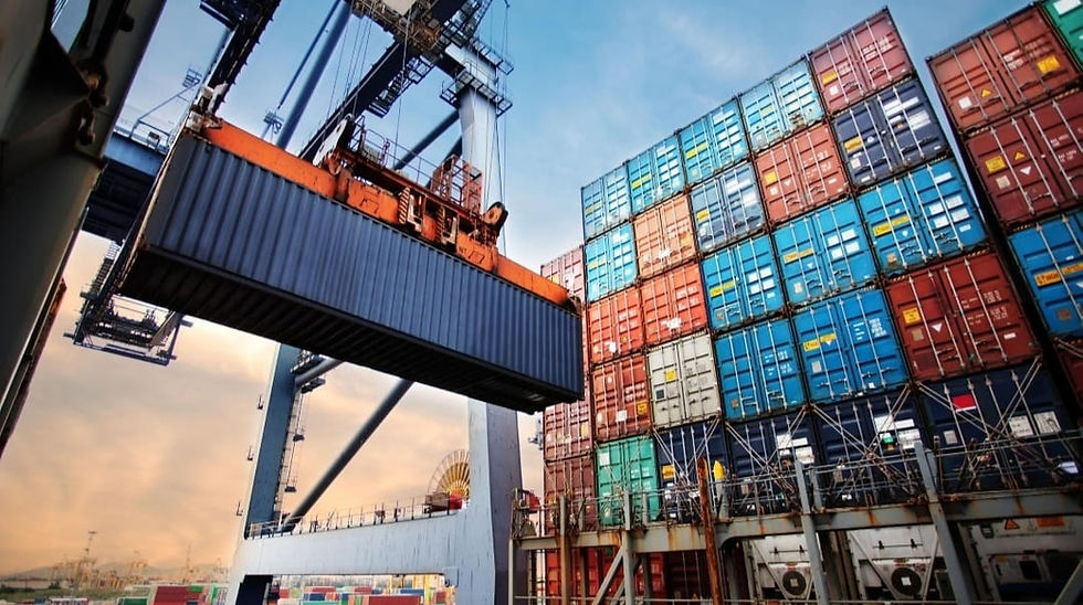 Port crane lifting a container beside stacked cargo.