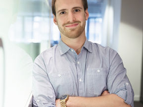 Joven directivo escolar sonriendo mientras reflexiona sobre su papel como líder en la escuela