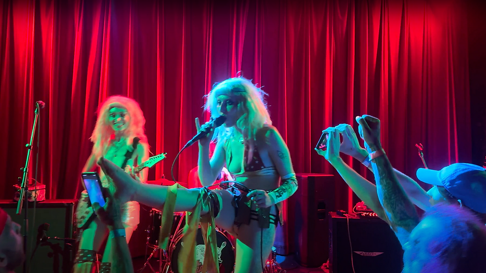 The SoapGirls performing on stage at RecordBar in Kansas City, with colorful lighting, dramatic stage presence, and fan interaction during their punk rock concert.