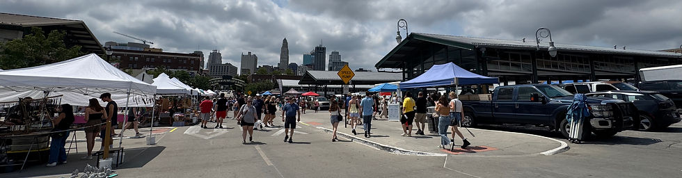 Crowds shopping at the City Market outdoor farmers market in Kansas City, Missouri, with downtown skyline in the background