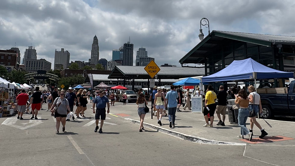 Crowds shopping at the City Market outdoor farmers market in Kansas City, Missouri, with downtown skyline in the background