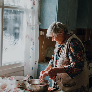 Starija žena priprema ručak u svojoj kuhinji