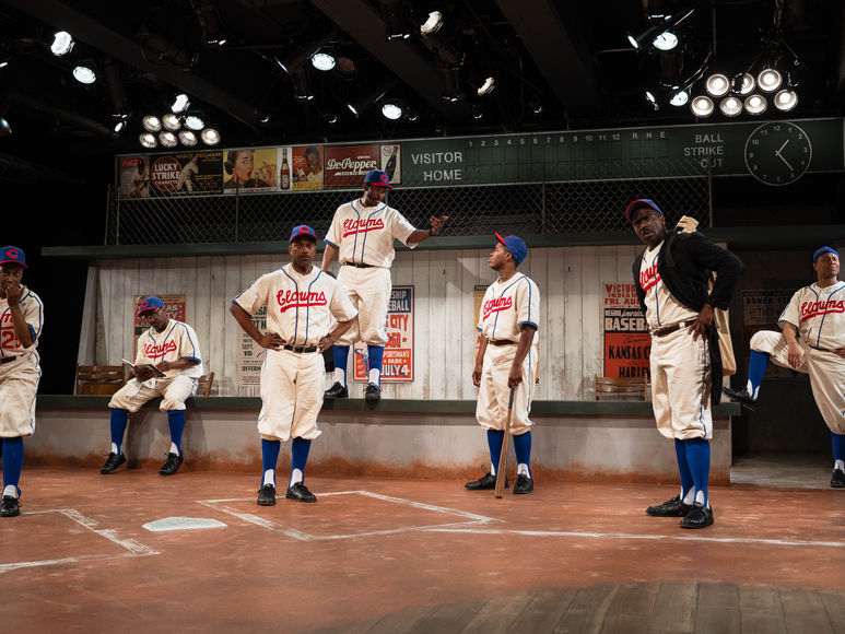 Tony King as King Tut standing on a field in a heated moment with the entire ensemble from Toni Stone, preparing to head back to the bus.