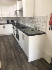 Clean kitchen with white tiles and a grey LVT floor