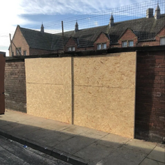 Two large windows that have been boarded up.png