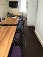 Meeting room with wooden tables and purple upholstered chairs