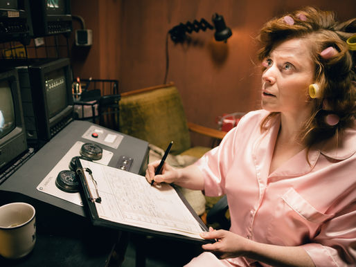 Eine Frau sieht auf einen Bildschrim mit Klemmbrett in der Hand.