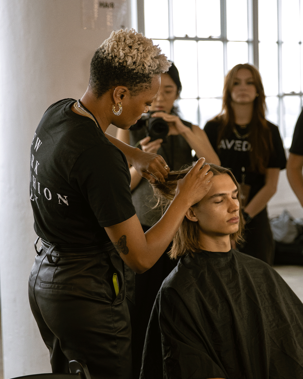 woman doing model's hair with group looking