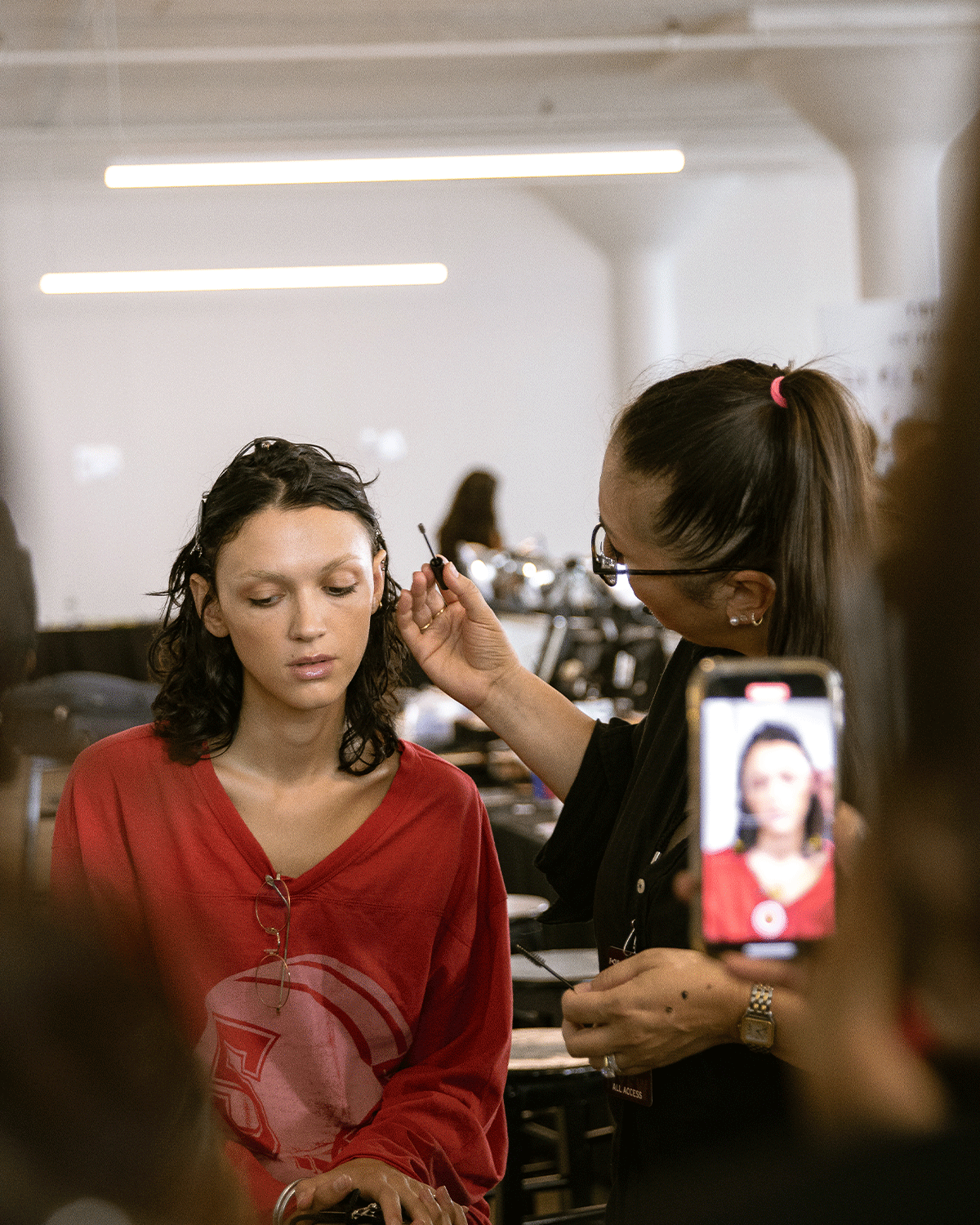 woman doing a model's makeup in front of a group