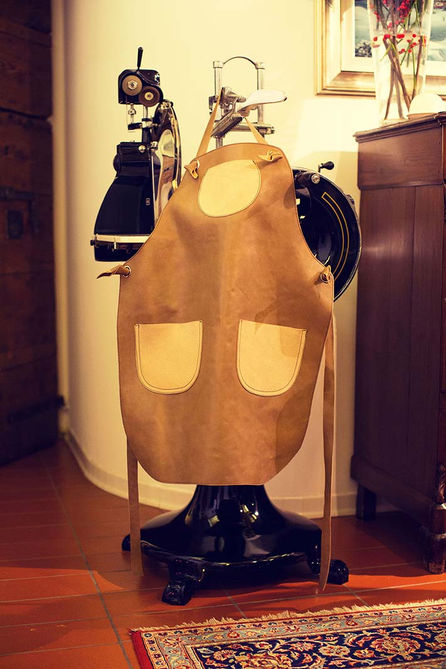 Full-grain leather craftsman apron with pockets in an atelier.