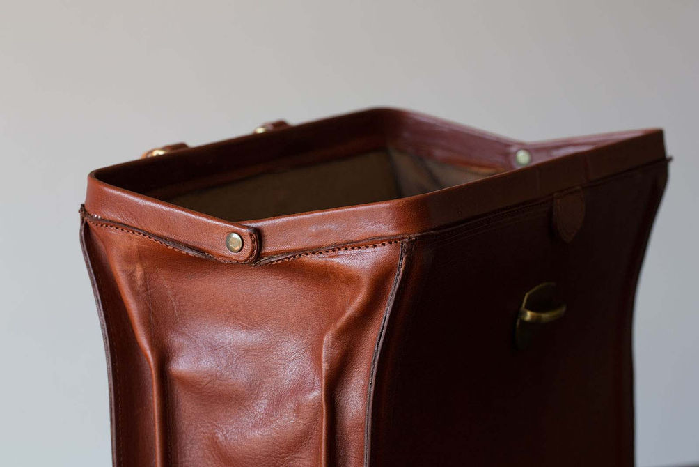 Vintage bag frame detail with brown leather and brass rivets.