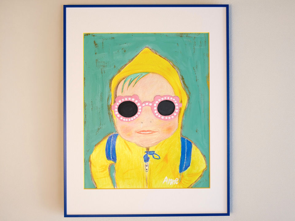 Portrait of a girl wearing a yellow hoodie and oversized pink sunglasses against a muted green background.