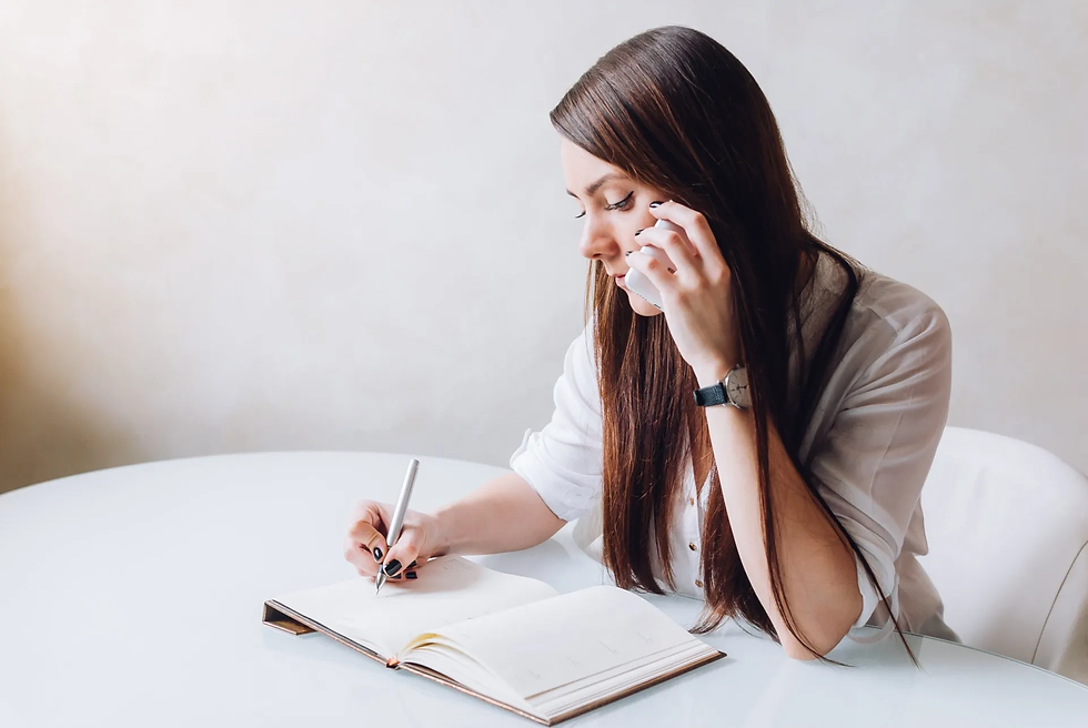 A lady taking notes while answering a phone call