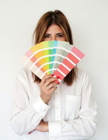 אישה מחזיקה פלטת צבעים צבעונית, מבחר גוונים, לבושה בחולצה לבנה, בחירת צבע.