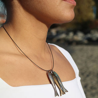 Model wearing an approximately 7cm articulated fish which is fish shaped and cut into 6 pieces. Fish is made of a base metal coated in silver plate then patinated with a black patina to give an aged effect. Fish is hung on an approximately 17 inch strong black marine 1 cms wire with sterling silver lobster clasp and fittings.