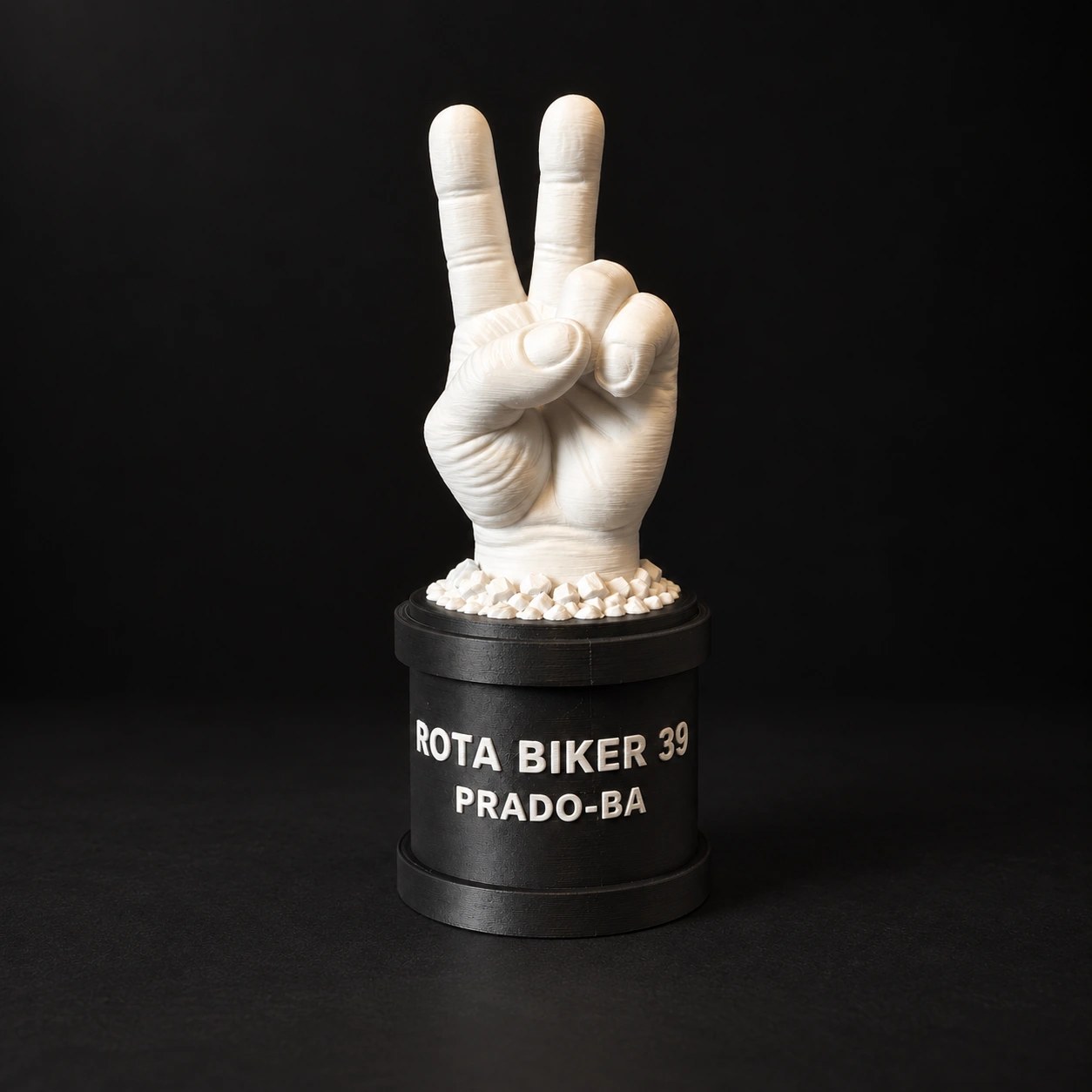Mini monumento Rota Biker 39 Prado: mão branca sobre base cilíndrica preta
