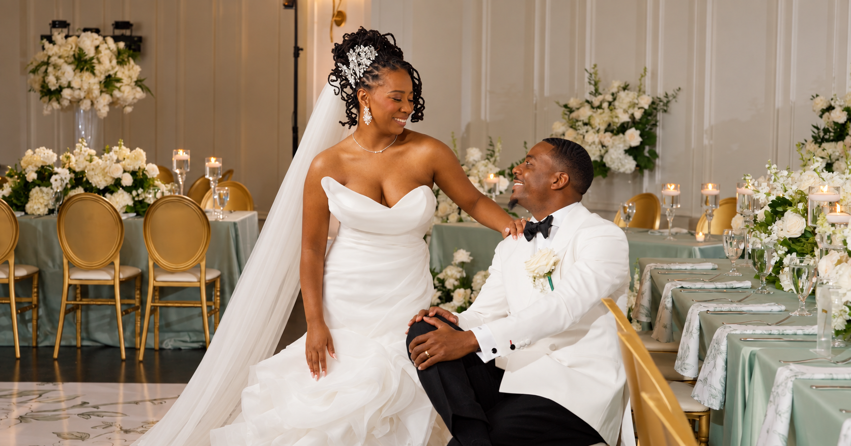 Smiling bride standing beside her seated groom at their wedding reception