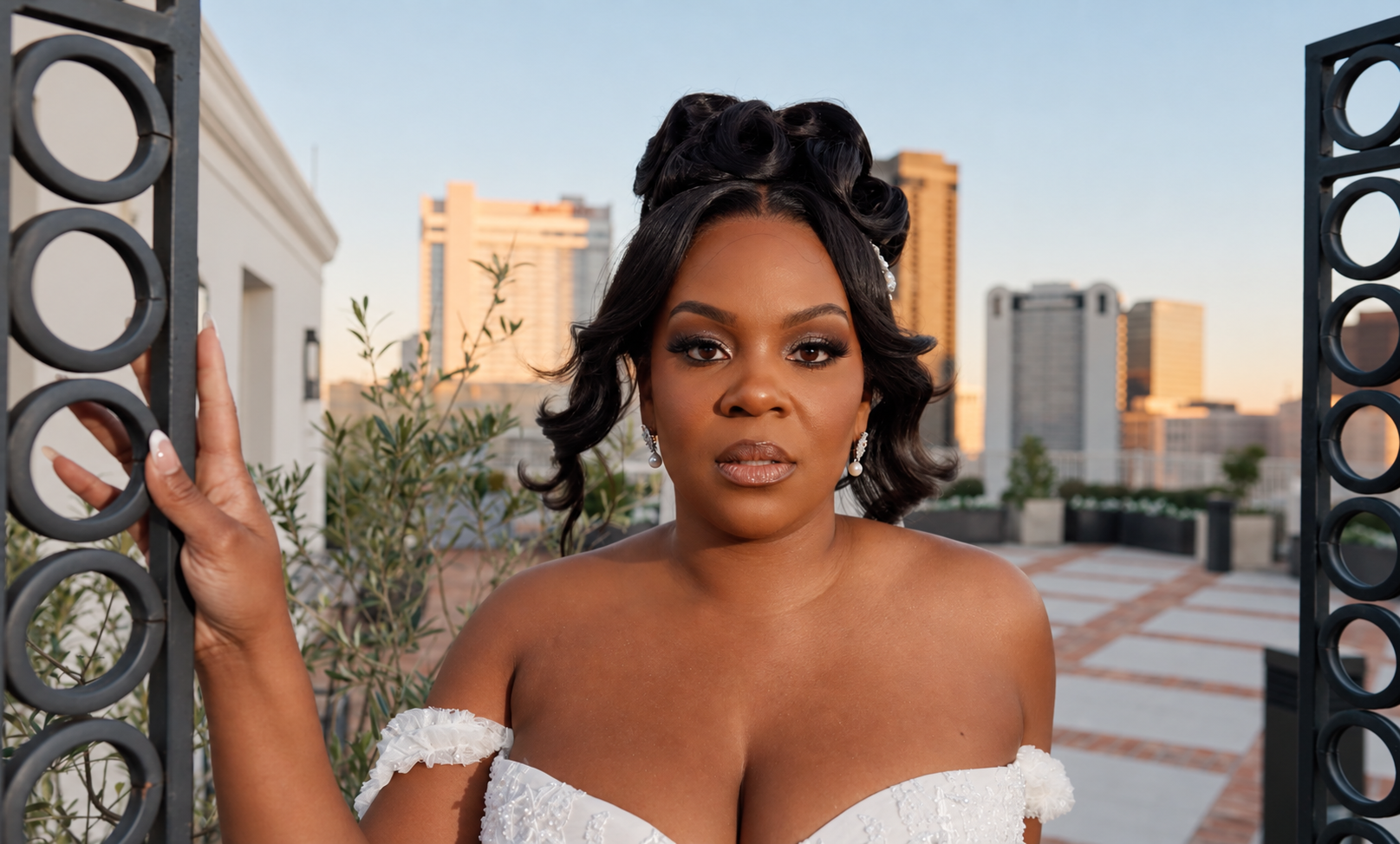 Bride posing beside a curved rooftop railing with a city skyline in the background