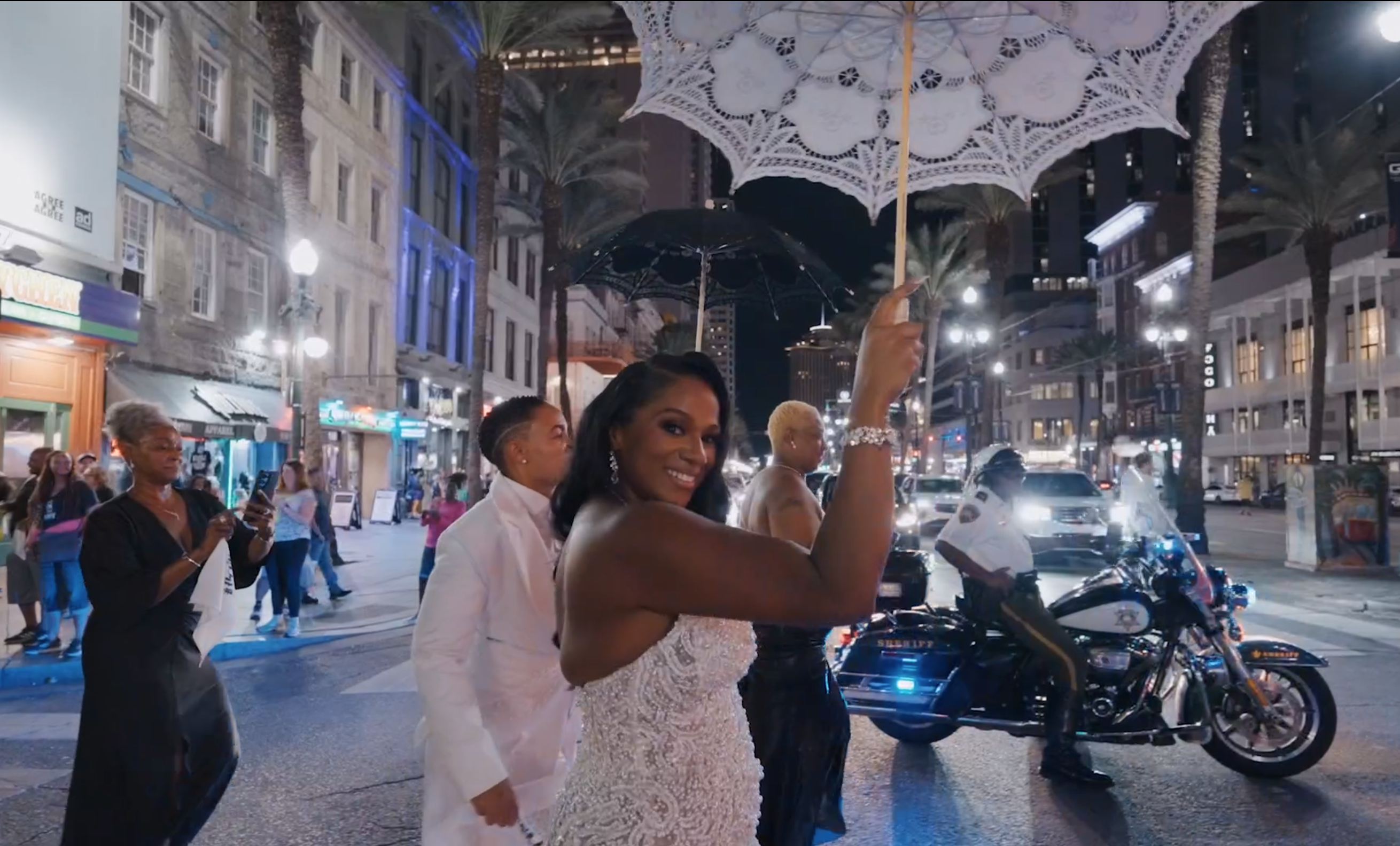 Bride holding a white lace umbrella during a nighttime wedding celebration on a city street