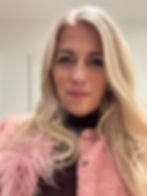 Frau mit blondem Haar und rosa Jacke mit Federbesatz