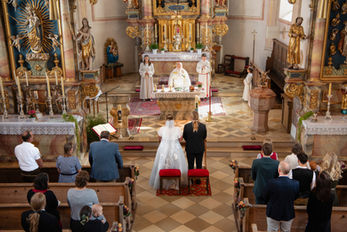 Brautpaar heiratet in einer prächtigen Kirche vor einem Priester.