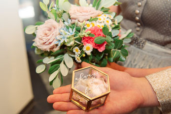 Hände halten sechseckige Ringbox 'always love for', Blumenstrauß Hochzeit.