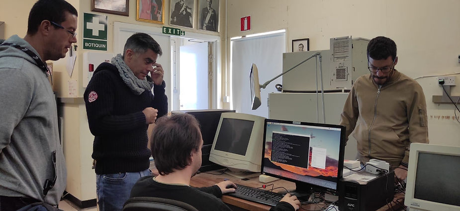 In the Carlsberg Meridian Telescope Office. One person working on a computer and two people looking on, with another person working on the other side of the table.