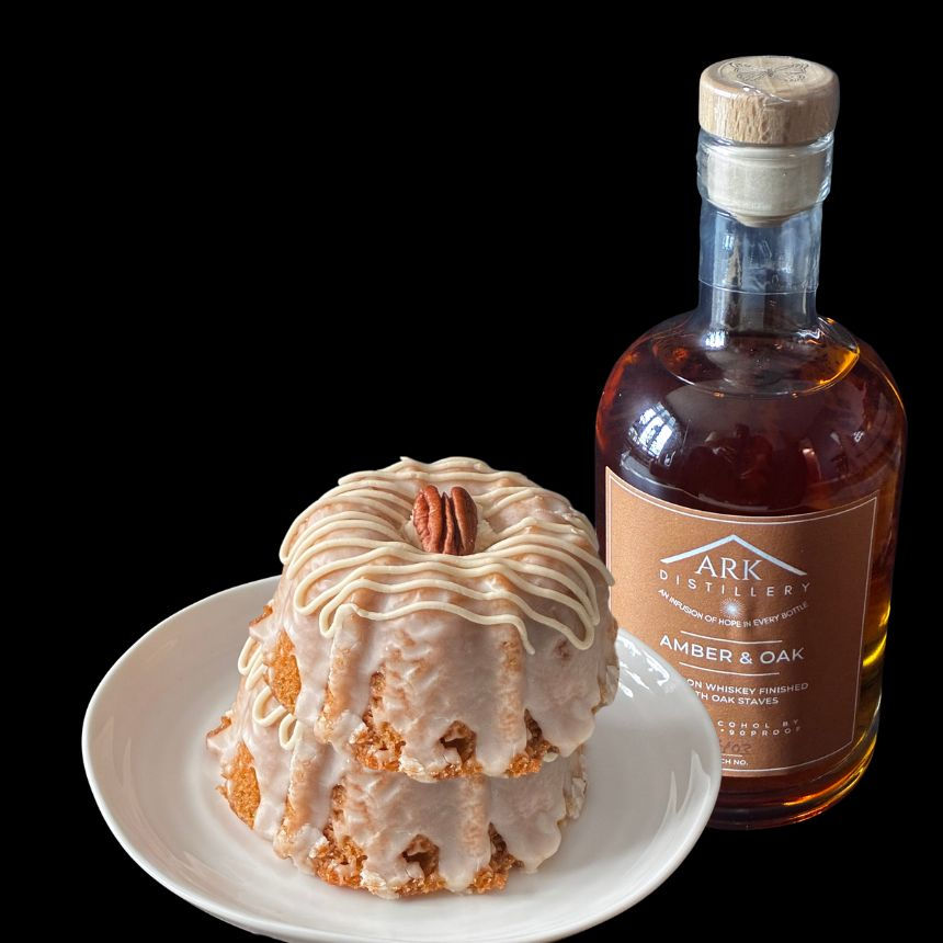 Two mini Maple Bourbon Pecan Bundt cakes on a white plate beside a 375ml bottle of ARK Distillery Amber & Oak Bourbon